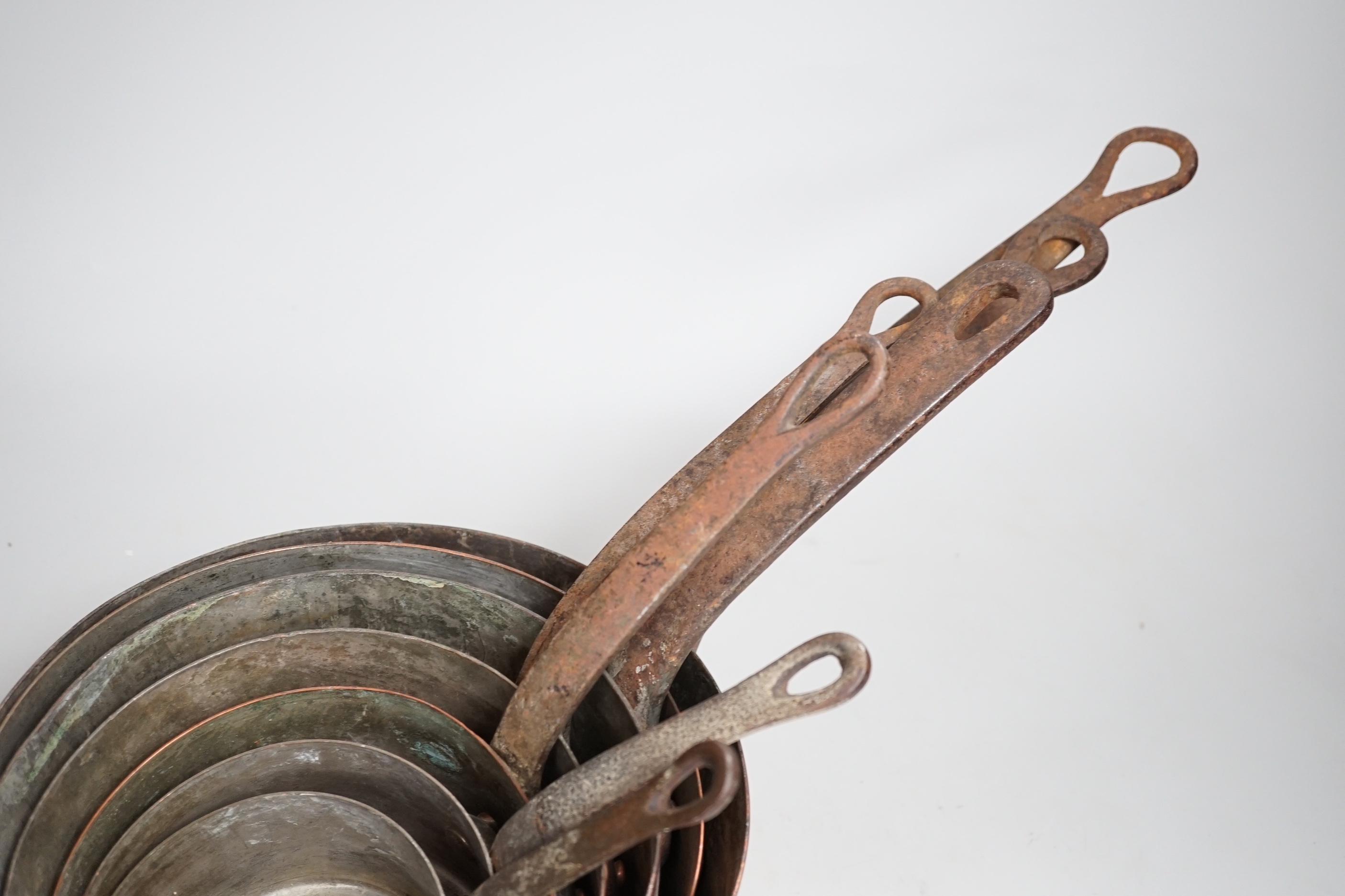 A graduated set of seven copper pans, the largest 47cm wide